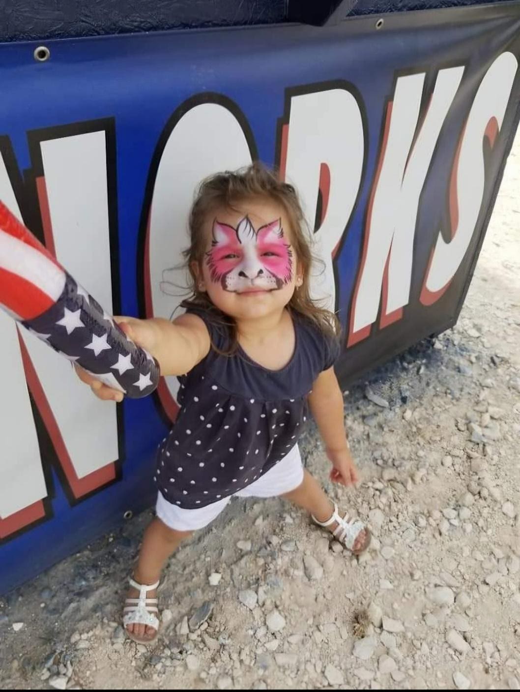 Girl with face paint holding a toy flag.